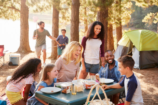 Family With Friends Camp By Lake On Hiking Adventure In Forest