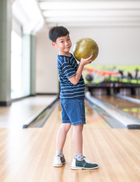 Portrait Cute child with ball in bowling club