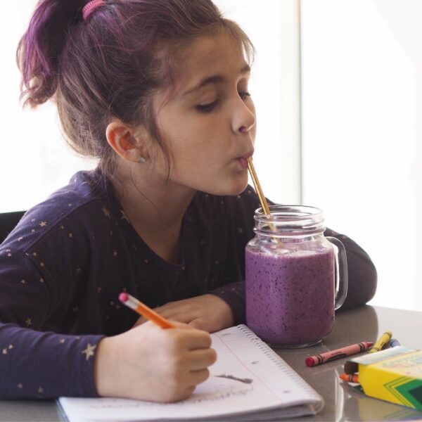 little girl drinking blueberry smoothie
