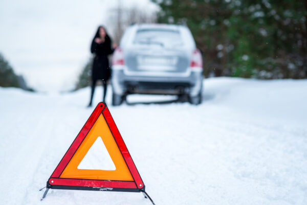 Winter driving - car breakdown Car breakdown on a country road in winter. Woman standing beside her car.