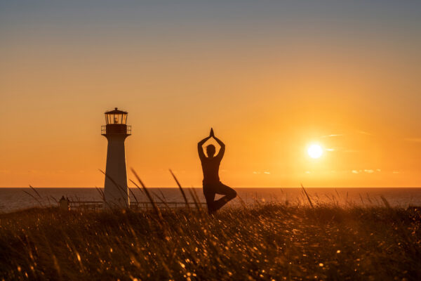 Yoga at sunset in front of lighthouse.