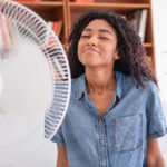 Black woman refreshing in front of a fan during summer heat