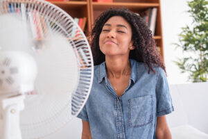 Black woman refreshing in front of a fan during summer heat