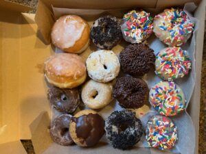 A box filled with more than a dozen doughnuts of a different varieties.