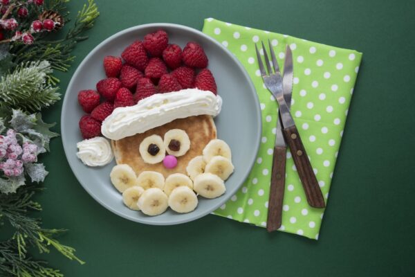 Fun food for kids. Christmas Santa pancake with raspberry and banana for children menu, top view with copy space for text.